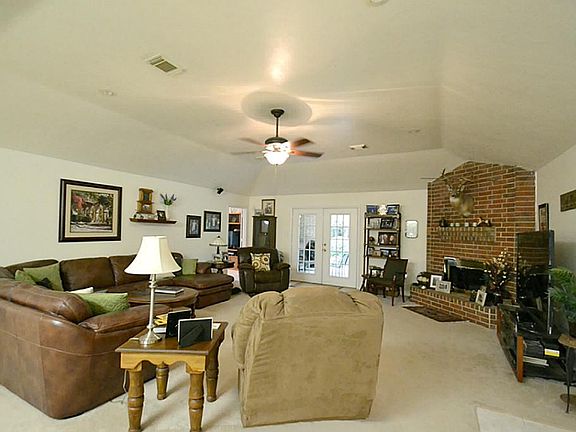 SPACIOUS DEN WITH CORNER WOOD-BURNING FIREPLACE & FRENCH DOORS THAT LEAD TO THE COVERED BACK PATIO. CEILING FAN. CARPET.