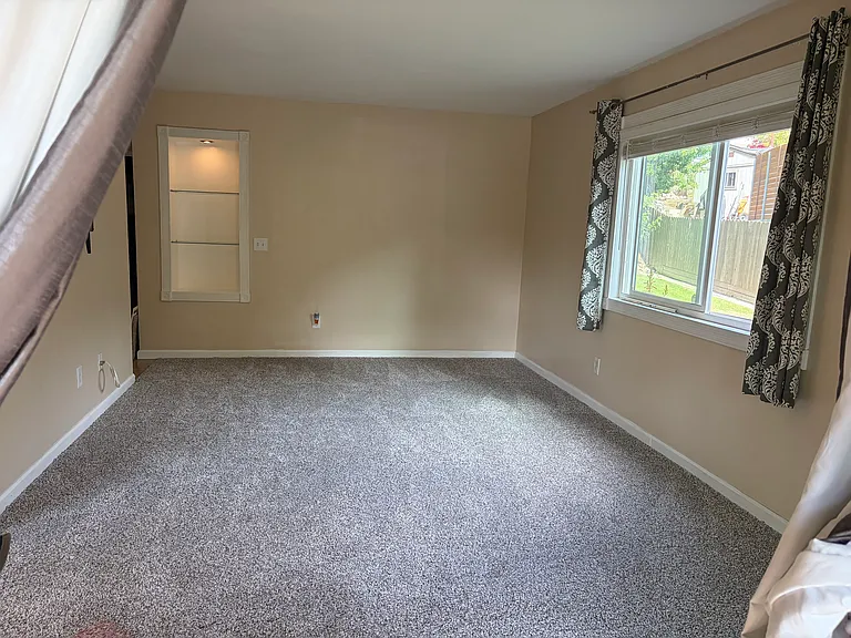 Large living room with new carpet and privacy out large window abutted by landscaping and no views of other residences.