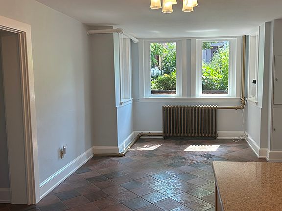 Large living room with south-facing sunny morning windows, hot water radiator heat and AC window unit.