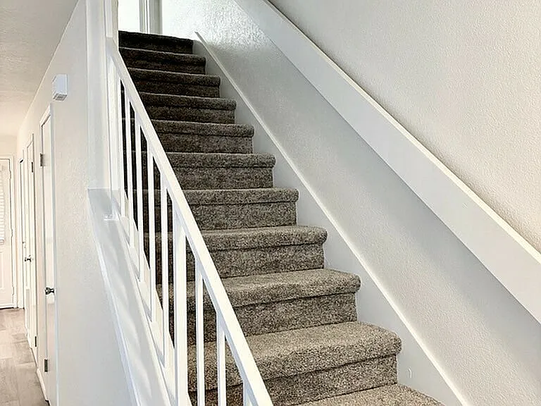 Ascend in style with this beautifully designed staircase, featuring plush carpeting and bright, welcoming ambiance.