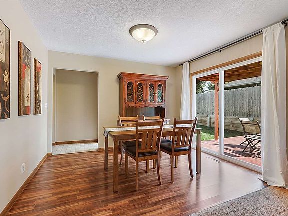 Sun drenched dining room is connected by patio doors to pergola covered deck