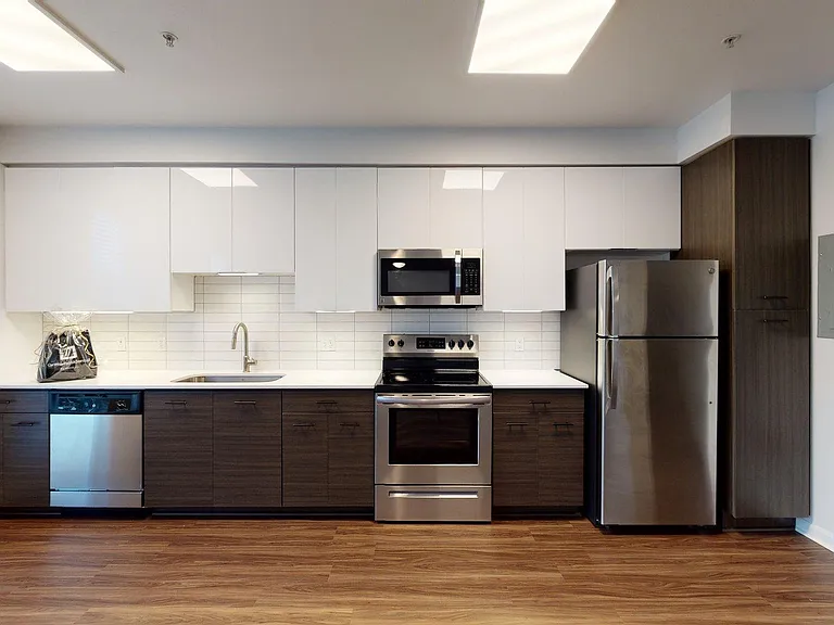 Apartment Kitchen with Stainless Steel Appliances, Quartz counter tops and Wood Style Flooring.