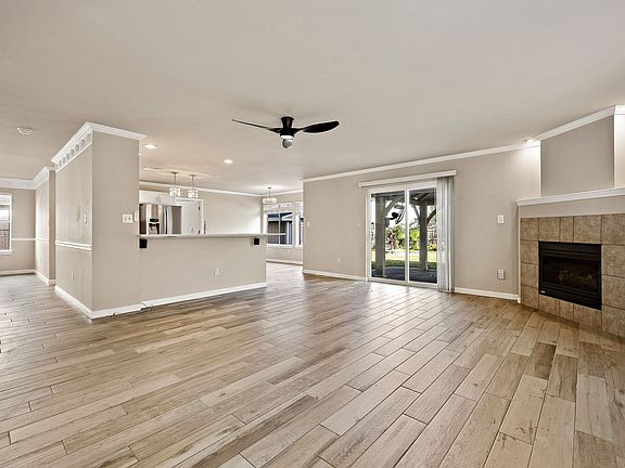 Large living room with wood-looking tile flooring, modern light fixtures and a fireplace