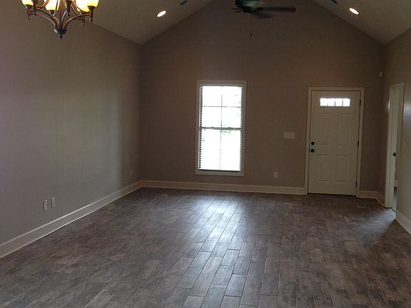 Large den with vaulted ceiling. Wood plank tile flooring throughout den, dining, kitchen and laundry areas.