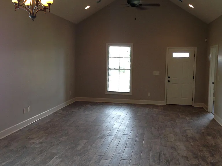 Large den with vaulted ceiling. Wood plank tile flooring throughout den, dining, kitchen and laundry areas.