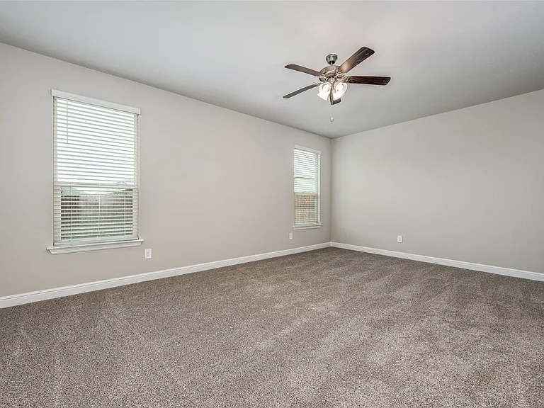 Carpeted empty room featuring ceiling fan