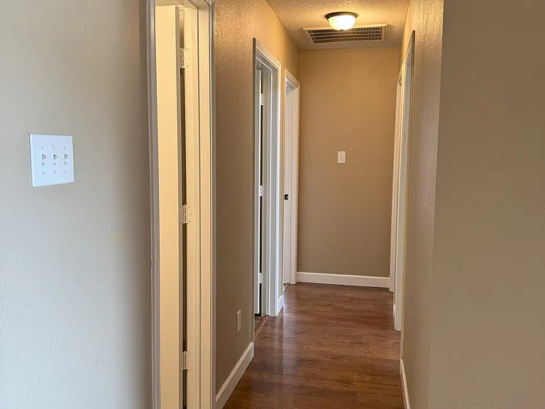 Hallway off to the right side of the front door, leading to three bedrooms and a hallway bathroom.