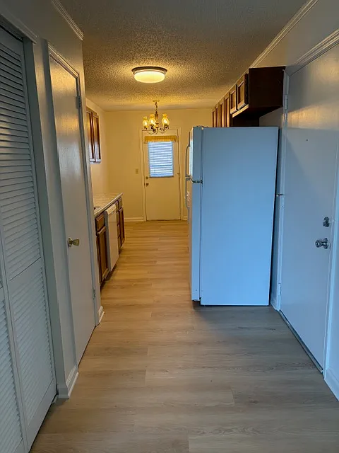 Front door to the right. Length of kitchen to balcony door