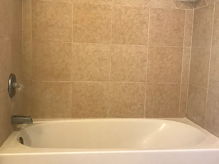 Full sized bathtub with tile surround.