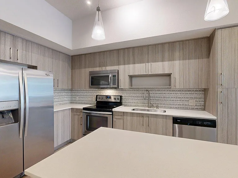 Apartment kitchen with stainless steel appliances and light counters.