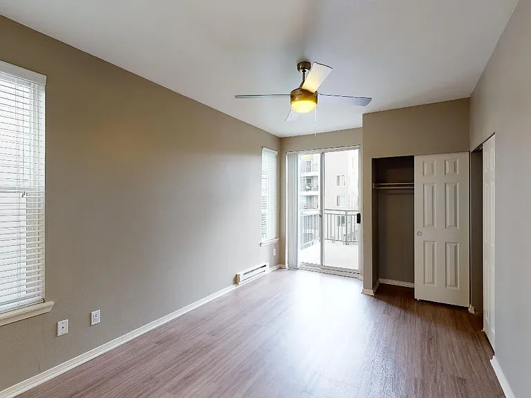 Spacious apartment bedroom with wood-style flooring and balcony access.