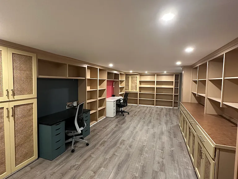 Basement with able built-in storage space and two desks.