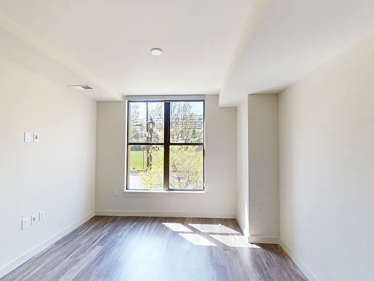Spacious apartment bedroom with wood-style flooring.