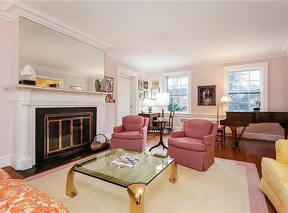 Seen from the opposite end, the living room with its detailed Crown moldings and elegant fireplace has views of the front yard.