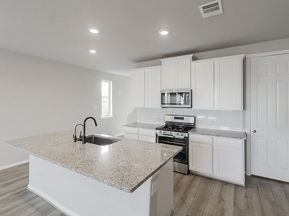 This kitchen is a chef s dream. The spacious kitchen features white cabinetry, granite countertops,
