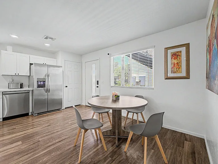 Eat-in kitchen and dining area with stainless-steel appliances, ample cabinetry, and a round table beside a large window.