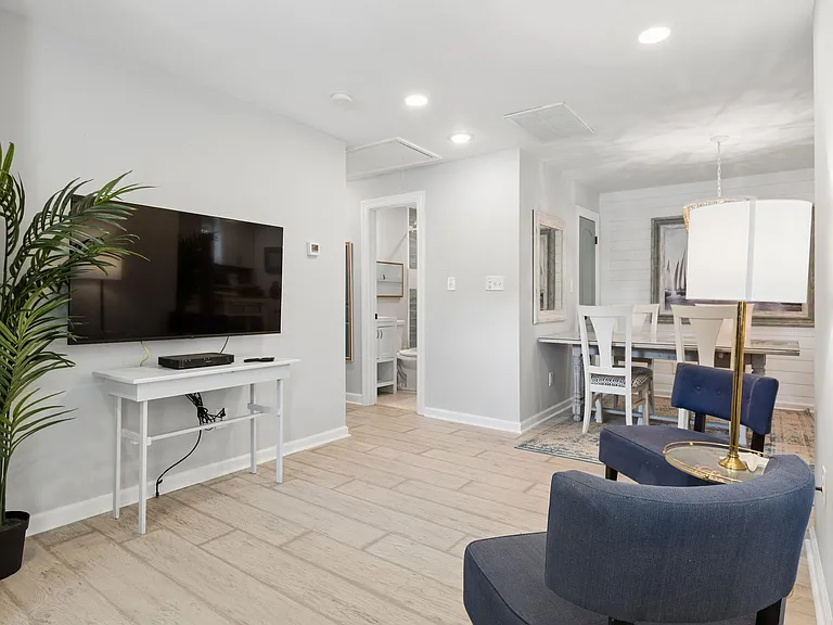 Open living and dining area with wall-mounted TV, dining table seating, and easy flow to the adjacent bathroom.