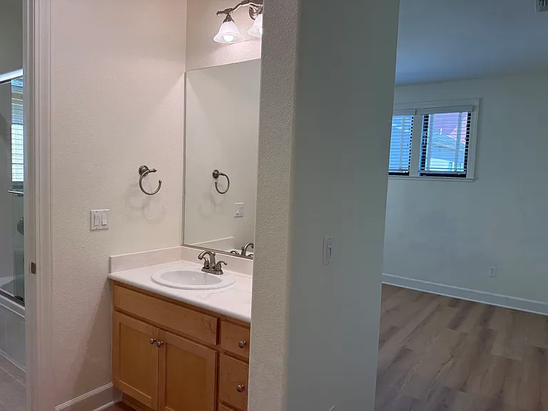 Spacious Bedroom #1 features multiple windows, vinyl flooring, walk-in closet, a separate bathroom sink and share a Jack-and-Jill style bathroom for the bathtub and toilet.