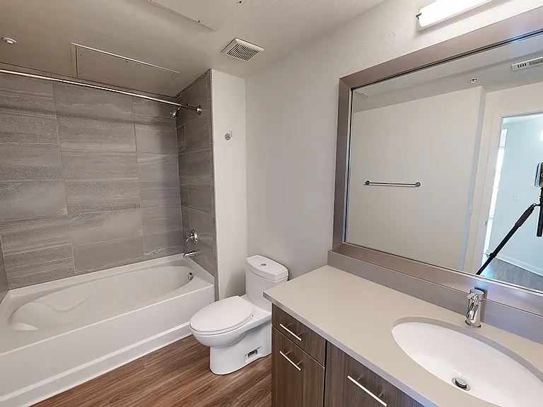 Apartment bathroom with large soaking tub and wood-style flooring.