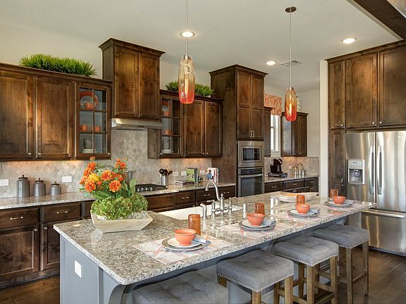 Kitchen with island, granite countertop, backsplash, dark cabinetry and hardwood floors