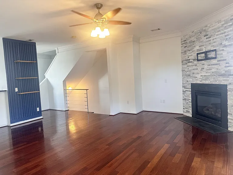 Spacious living-room with stone wall, gas fireplace, and bookshelves.