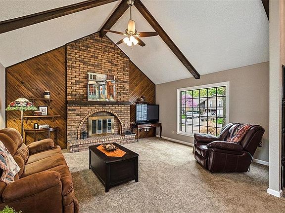 Great room features vaulted ceiling with wooden beams, masonry fireplace with gas starter and an abundance of natural lighting.
