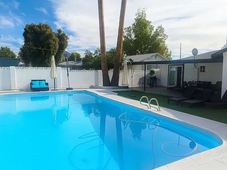 Resort-style backyard features a large swimming pool, lounge seating, and shaded patio areas for relaxing or entertaining.