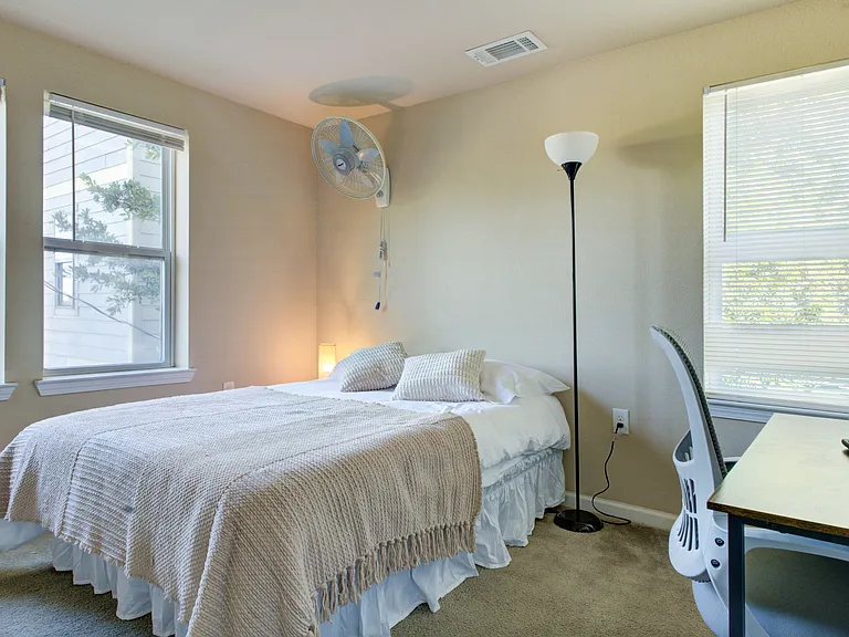 Bedroom features large windows with blinds, a full bed, and a dedicated desk area ideal for work or study.