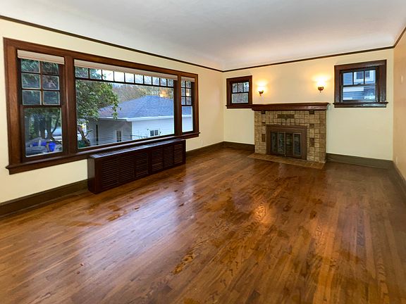 Main floor living room with hardwood floors, coved ceilings, large windows with new blinds, picture rail moldings, and an original Batchelder fireplace.