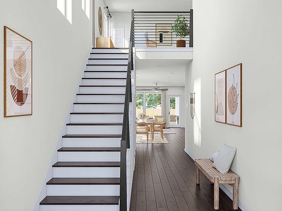 A modern, minimalist interior with a wooden staircase leading to an upper level, surrounded by white