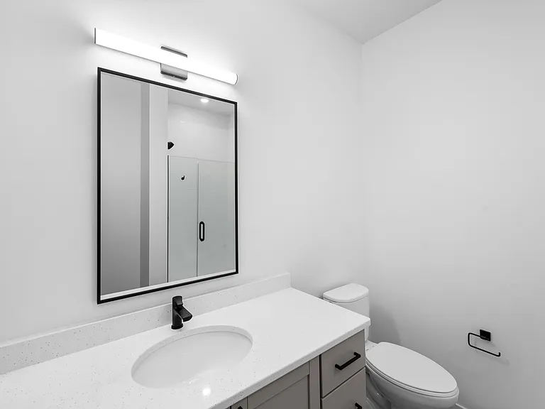 Modern bathroom with sleek fixtures, illuminated mirror, and glass shower enclosure. Modern bathroom with sleek fixtures, illuminated mirror, and glass shower enclosure.