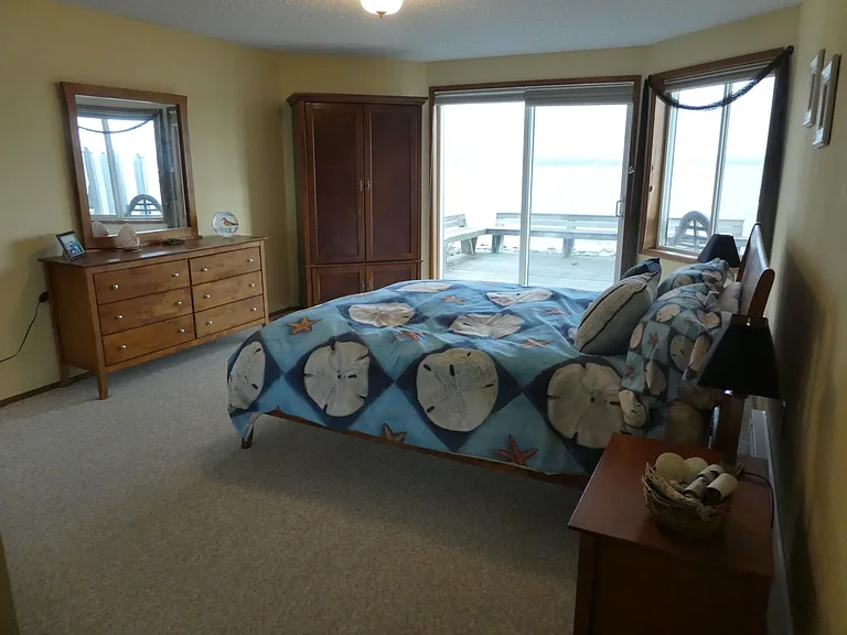 Primary bedroom overlooking bay and mountains with sliding door to deck.