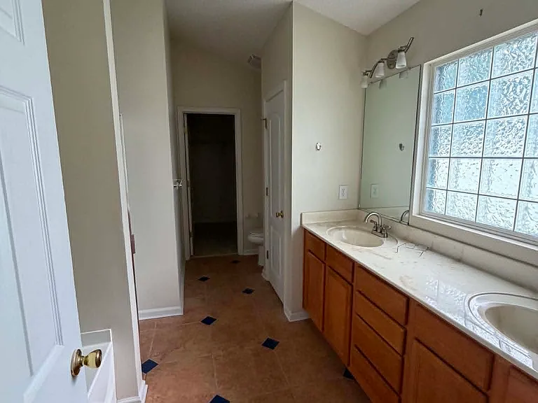 Spacious primary bathroom featuring dual vanities, a jetted soaking tub, separate walk-in shower, and a large walk-in closet.