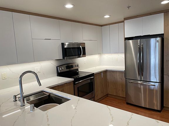 A very spacious kitchen with electric stove and a contemporary sink.