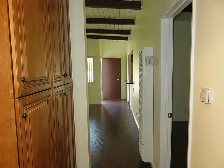 View is looking down the hallway to front door while standing at by the washer/dryer.