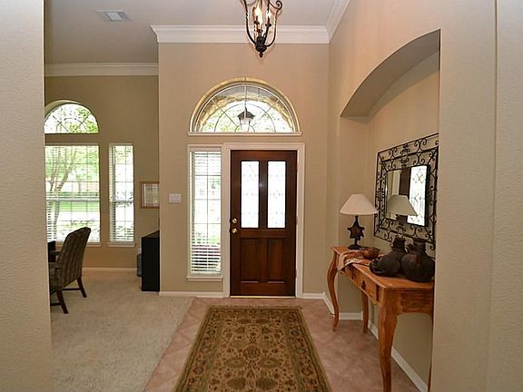 Elegant entry offering a beveled glass front door, pretty arched window above, tile floors, niche and double crown molding. lovely light fixture.