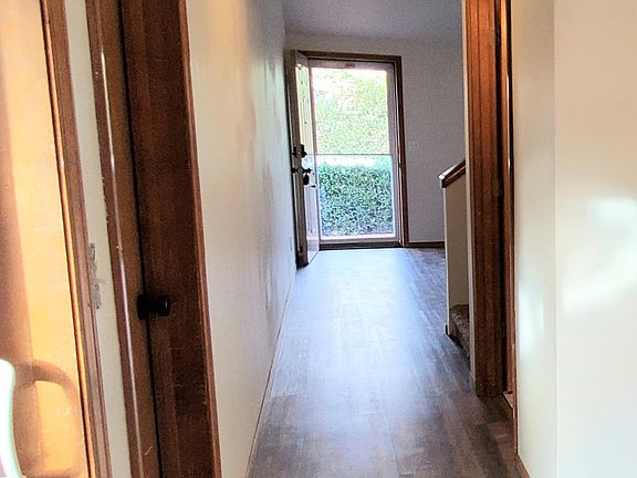 View from dining room with patio door and garage door to the left. Bathroom door to right with laundry room and utility room containing water heater.