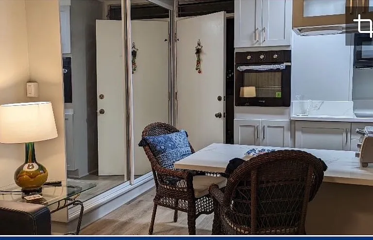 Standing in living room, looking toward the kitchen front door entrance. On left, the kitchen pantry with large mirrored double doors.