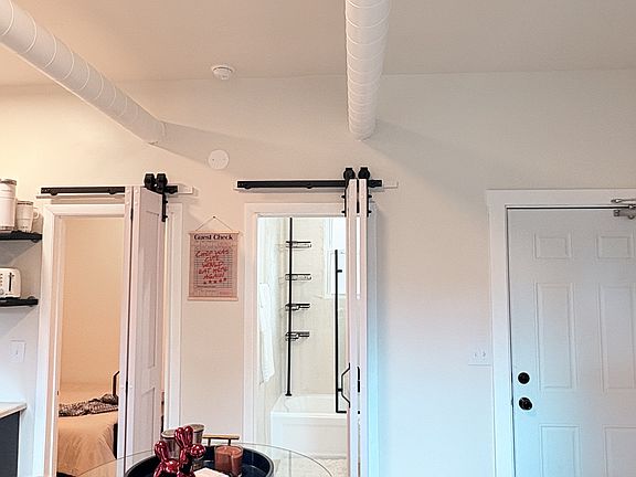 Open dining space with sliding barn doors leading to primary bedroom and bath