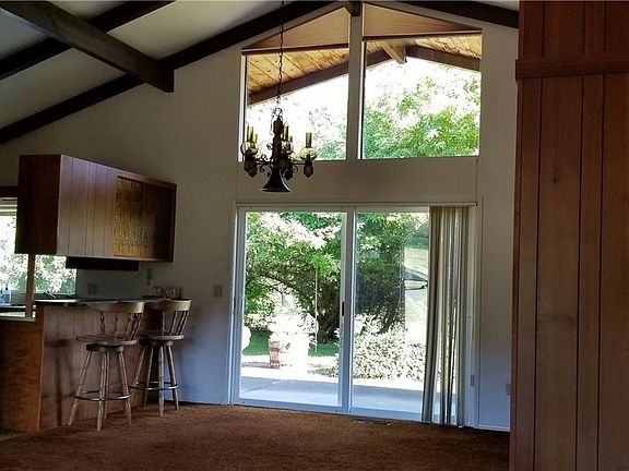Beyond the sliding glass doors are the patio, deck and a yard full of fruit trees.