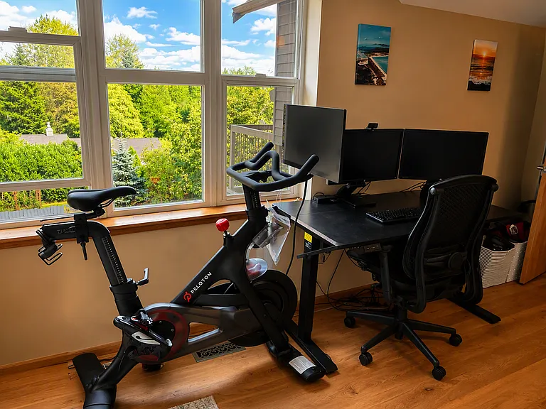 Very large media room with study area, television, large sofa, peloton