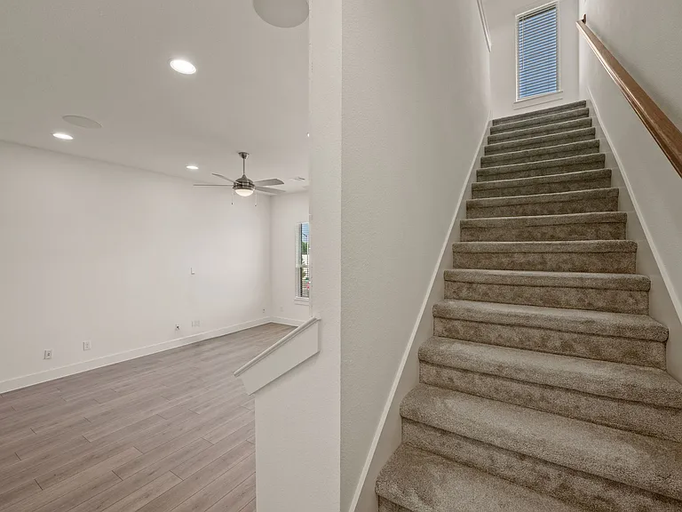 Stairway to third floor and view of the living area and multiple ceiling-mounted, recessed speakers.