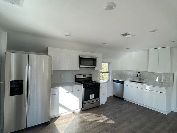 Contemporary kitchen with quartz countertops, marble-style backsplash, and stainless-steel appliances.
