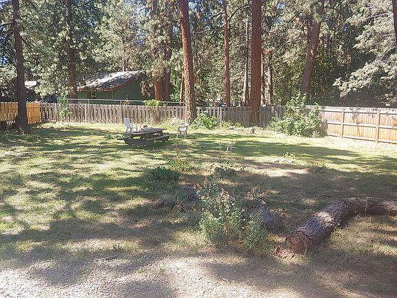Fenced back yard w/ rolling gate entrance. 2 garden beds, picnic table in the back with a large fire pit.