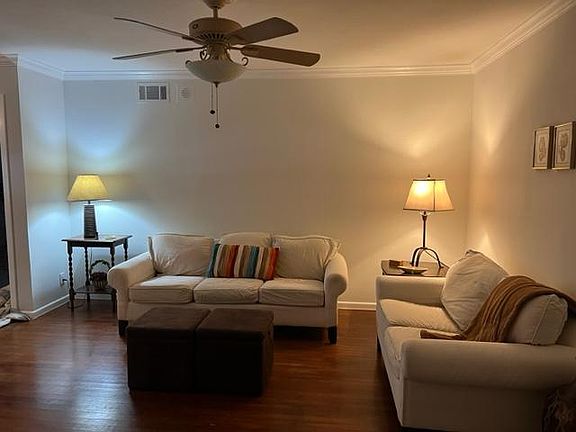 Living room with hardwood floors, crown molding, and ceiling lighted fan.