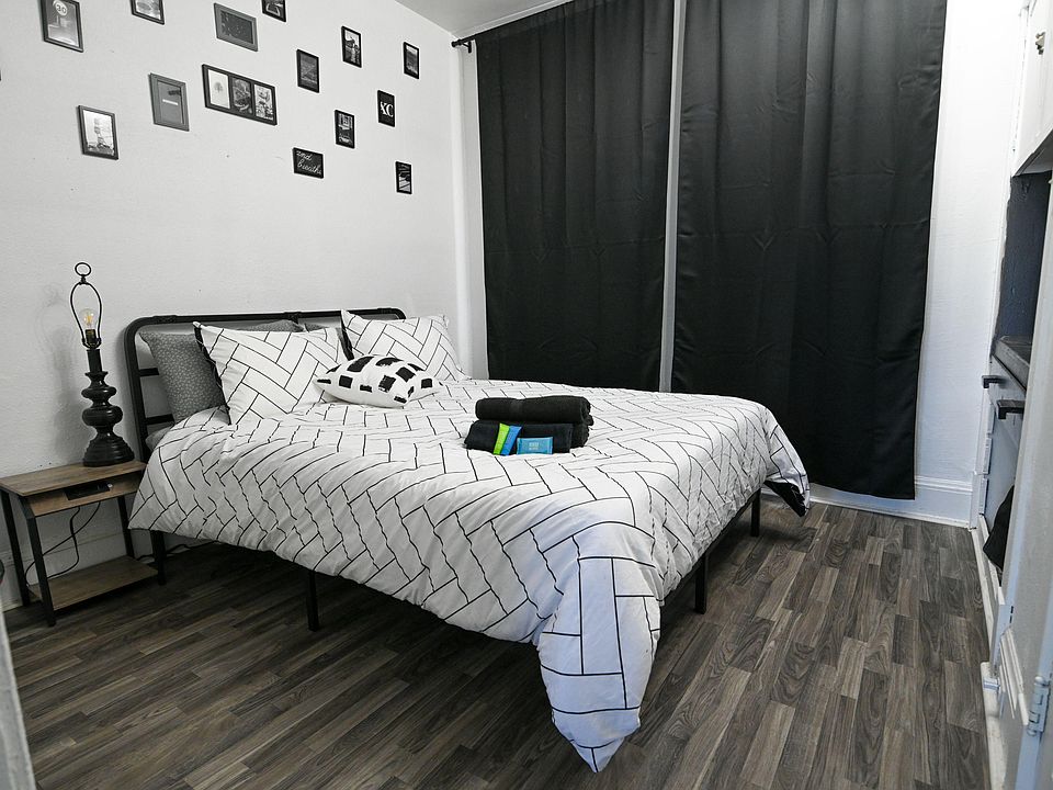 Furnished bedroom with a full bed, nightstand, and wall art, plus blackout curtains and durable wood-look flooring.
