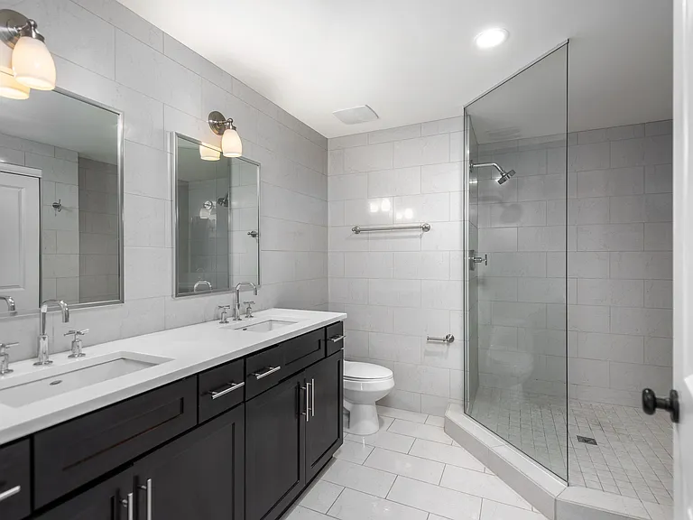 York House design bathroom with quartz countertops, oversized custom shower with glass doors and floor-to-ceiling tile.