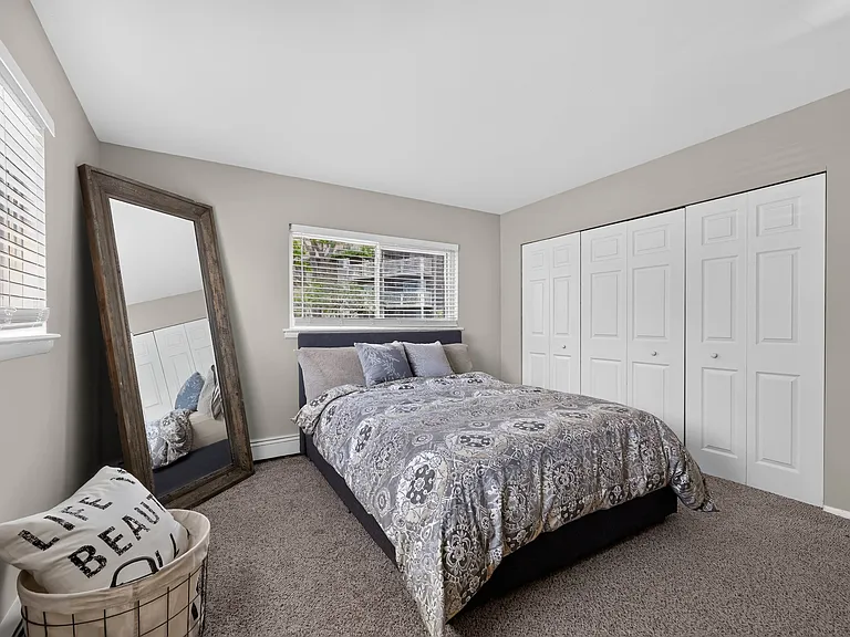 Relax in a spacious bedroom complete with a wall mirror at Renaissance at Carol Stream in Carol Stream, IL.