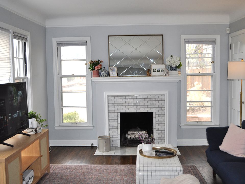 Bright and sunny living room features a decorative fireplace, coved ceilings, and restored hardwood floors