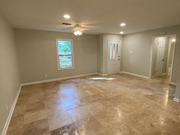Living room and entry area, looking towards front door from the dining area. Tile flooring throughout for easy cleaning.
